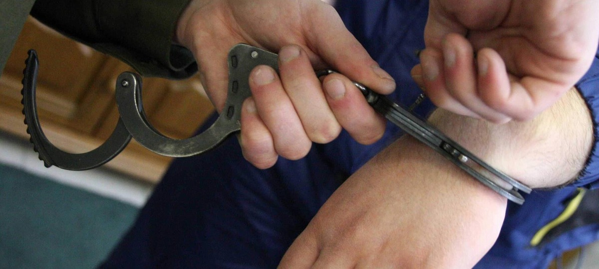 Мужчине надевают наручники на руки при задержании