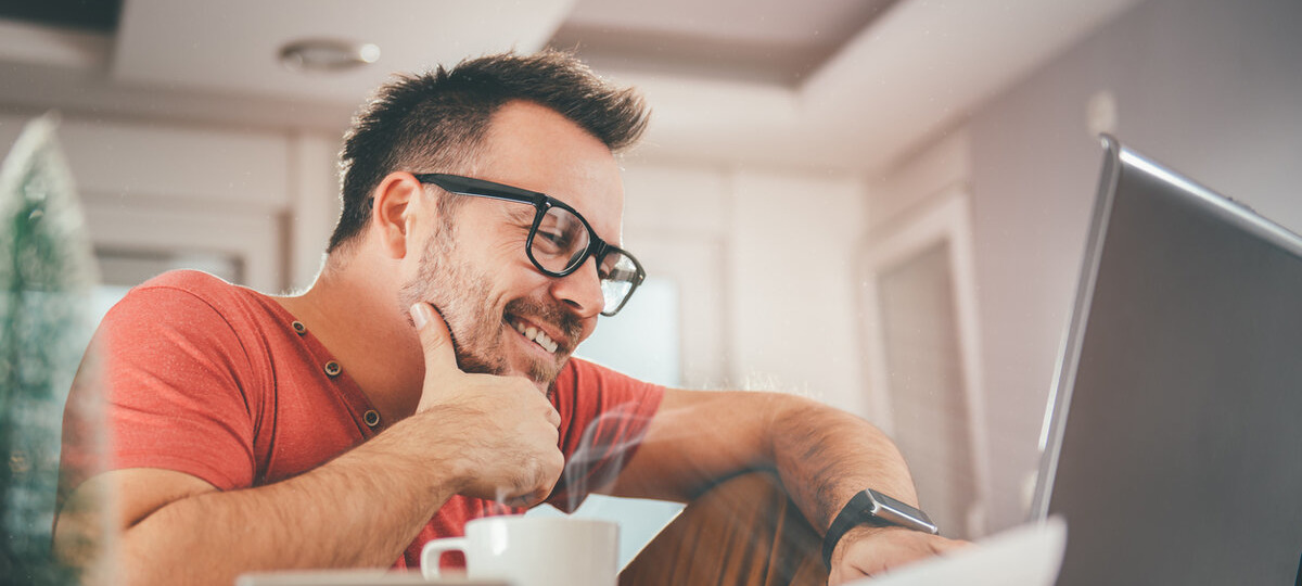 Мужчина смотрит в компьютер и улыбается