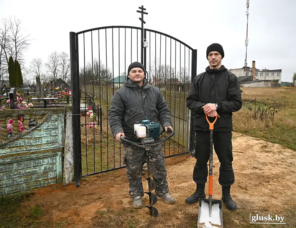 рабочие стоят возле кладбища с ломатами