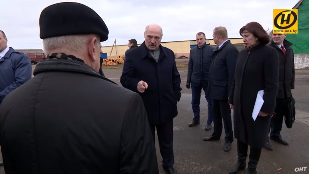 Александр Лукашенко на выездном совещании с чиновниками и представителями местной администрации. Зимняя одежда, открытая площадка, промзона на фоне.